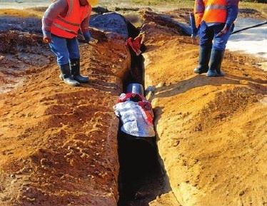 Workers laying pipe in a trench